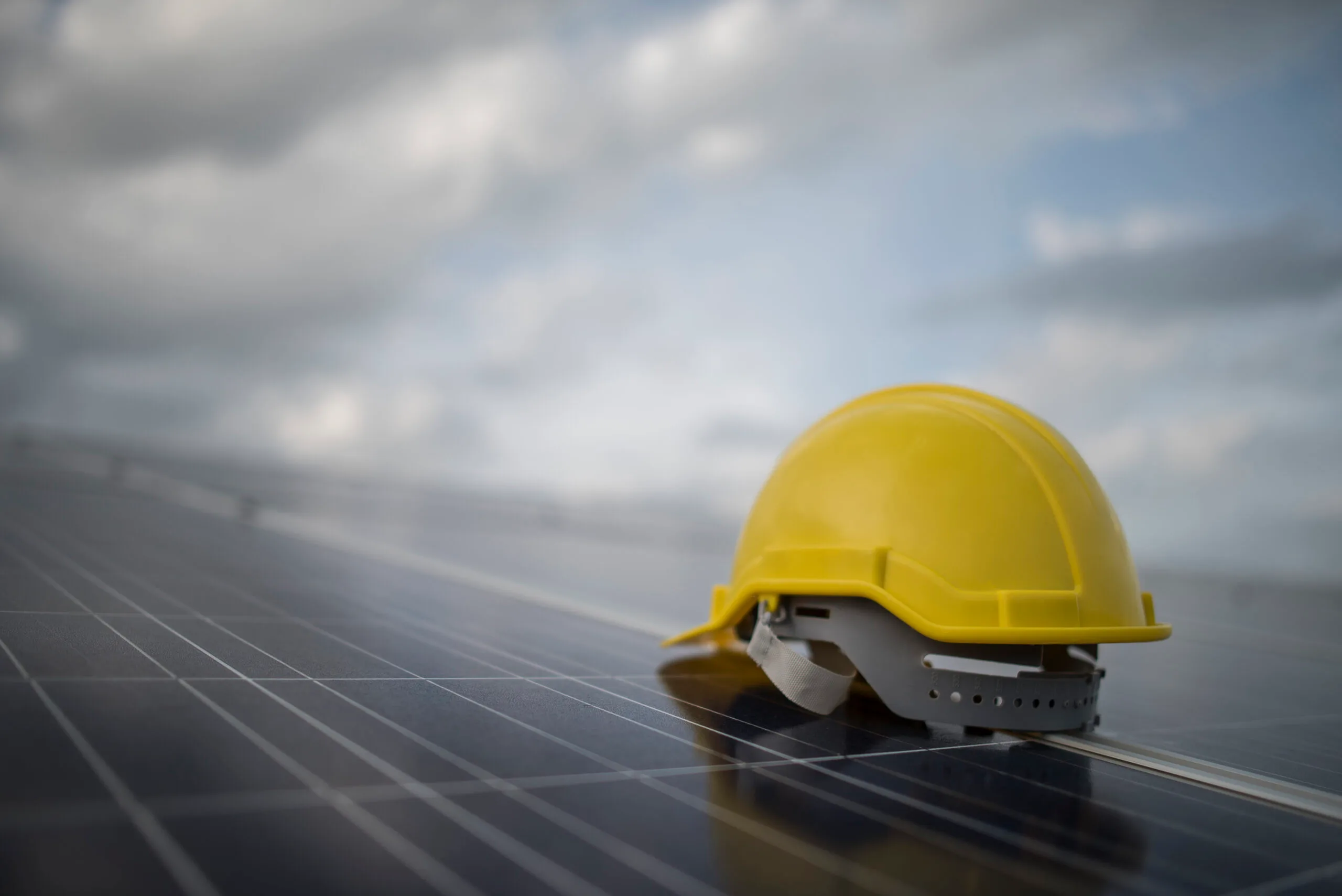 Casco de seguridad amarillo sobre panel solar - Estudio de Seguridad e Higiene Opus.